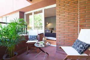 Apartment Barcelona Rentals - Classic Bonanova Apartment في برشلونة: فناء به كرسيين وطاولة وجدار من الطوب