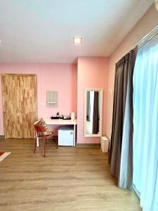ein Zimmer mit rosa Wänden, einem Stuhl und einem Schreibtisch in der Unterkunft The See Stay Hatyai in Hat Yai + 22 Fotos