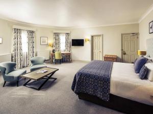 a hotel room with a bed and a table and chairs at Mercure Gloucester Bowden Hall Hotel in Gloucester +181 photos