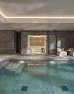 a swimming pool in a room with a couch and a bed at Oreno Mountain Retreat Hotel in Tsepelovo