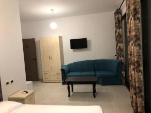 een woonkamer met een blauwe bank en een tv bij Actium in Vlorë +33 foto's