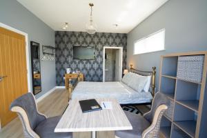 een slaapkamer met een bed, een tafel en stoelen bij Rest a While in Bushmills