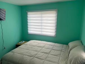 een slaapkamer met een groot bed en een raam bij CASA DEL CENTRo in Quellón