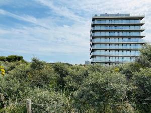 un grand bâtiment au sommet d'une colline avec des arbres dans l'établissement Windekind402, à La Panne