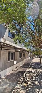 un edificio con ventanas enrejadas al lado de un árbol en alojamiento bella vista, en Villa Carlos Paz