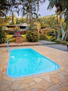 una piscina in un cortile con un parco giochi di Casa da Índia - Pousada Jussara a Joinville