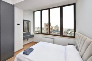 une chambre avec un lit blanc et de grandes fenêtres dans l'établissement Comfort Apartment, à Aghk'ilisa