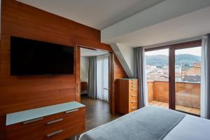 a bedroom with a flat screen tv on a wooden wall at Silken Monumental Naranco in Oviedo