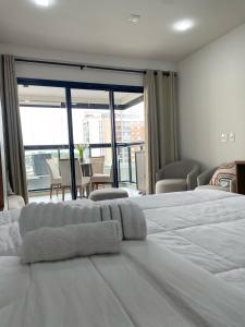 a white bed in a room with a large window at Flat Apartamento Av Esmeralda em Marília in Marília