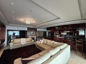 a living room with two couches and a kitchen at Mi Casa in Hartbeespoort