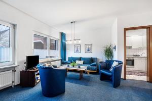 Ferienwohnung Dommel في كوكسهافن: غرفة معيشة مع كراسي زرقاء وأريكة وطاولة