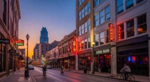 Menschen fahren mit dem Fahrrad eine Stadtstraße mit Gebäuden entlang in der Unterkunft AuthenticATXBeauty,Fireplace,Walkto6thSt,BestEateries,Barbeccue in Austin