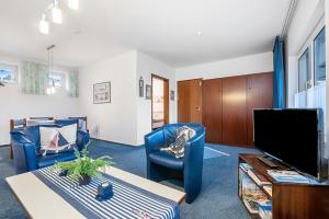Ferienwohnung Dommel في كوكسهافن: غرفة معيشة مع كرسيين ازرق وتلفزيون