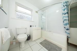 een badkamer met een toilet, een bad en een raam bij Modern 3BDR property in beautiful Swords Dublin in Swords +11 foto's