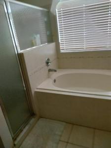 a bathroom with a tub and a shower and a window at La casa in Winter Haven