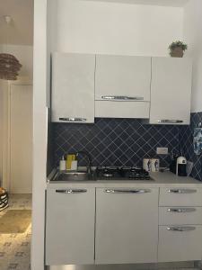 een keuken met witte kasten en een spoelbak bij VitaDaMare in Giardini Naxos +3 foto's