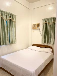 un letto bianco in una stanza con tende verdi di FSS Homestay a Coron