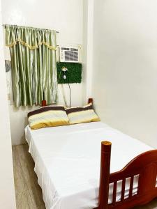 una camera da letto con un letto con lenzuola bianche e una finestra di FSS Homestay a Coron