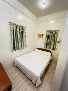 una piccola camera con un letto bianco e due finestre di FSS Homestay a Coron