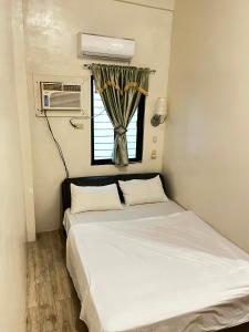 una piccola camera da letto con un letto e una finestra di FSS Homestay a Coron