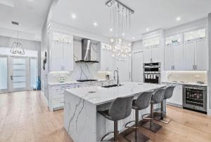 eine weiße Küche mit einer großen Insel mit Barhockern in der Unterkunft Spacious Three Bedroom Lakeside Home with Relaxed Coastal Comfort in Palm Beach Shores + 22 Fotos