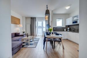 a kitchen and living room with a table and a couch at Apartamenty Aquamarina Onyx - visitopl in Międzyzdroje