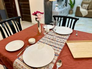 une table avec des assiettes et des verres et un vase avec des fleurs dans l'établissement Novo Stays - Artistic Boho Edition, à Hyderabad 23 autres photos