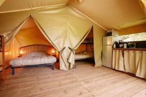 ein Schlafzimmer mit einem Zelt, in dem ein Bett und ein Kühlschrank stehen. in der Unterkunft Camping 4 étoiles - Parc aquatique - ccbcbhg in Caro + 82 Fotos