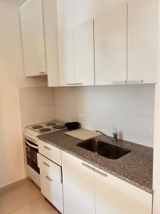 eine weiße Küche mit Spüle und Herd in der Unterkunft Departamento Sofia Soberana in Bahía Blanca
