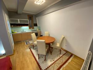 a kitchen with a wooden table and white chairs at Bjelašnica Babin do Apartman in SJJ +6 photos