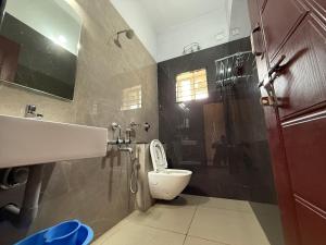 a bathroom with a toilet and a sink and a shower at Malpe Serene Stays in Malpe