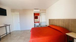 una camera da letto con un letto rosso e una cucina di Hotel Plaza del Ángel a Huajuapan de León