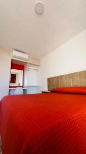 una camera con letto rosso e piumone di Hotel Plaza del Ángel a Huajuapan de León