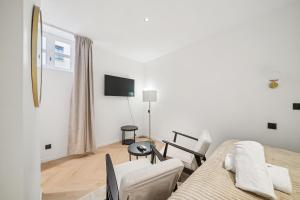 ein weißes Wohnzimmer mit einem Sofa und einem TV in der Unterkunft MyHotel - Suite Tête d'Or, Cordelier in Lyon