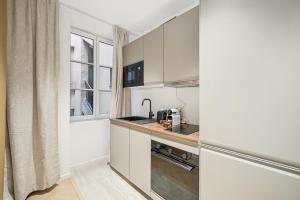 eine kleine Küche mit weißen Schränken und einem Fenster in der Unterkunft MyHotel - Suite Tête d'Or, Cordelier in Lyon