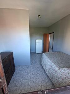 una camera da letto con un letto, una cassettiera e un frigorifero di Pousada em Ilhéus a Ilhéus