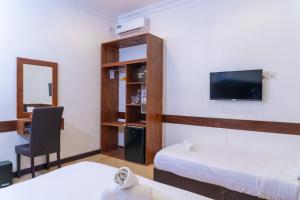 ein Zimmer mit zwei Betten, einem Schreibtisch und einem Fernseher in der Unterkunft Samaik Cottage in Thulusdhoo