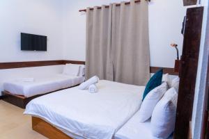 zwei Betten in einem Hotelzimmer mit Fernseher in der Unterkunft Samaik Cottage in Thulusdhoo + 3 Fotos