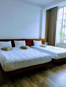 two beds in a bedroom with a window at New Pensive Villa in Nuwara Eliya