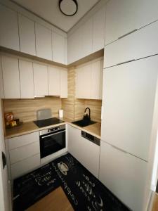 a kitchen with white cabinets and a sink and a rug at Bulevar Pent in Sarajevo