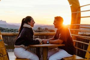 a man and a woman sitting at a table in front of the sunset at Glamping boutique bajo las estrellas in Archidona