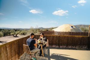a man and a woman sitting at a table on a balcony at Glamping boutique bajo las estrellas in Archidona