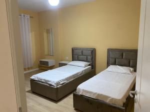 2 bedden in een kamer met 2 bedden, waarvan 1 tweepersoonsbed en 1 eenpersoonsbed. bij Cherry Apartments in Shkodër +9 foto's