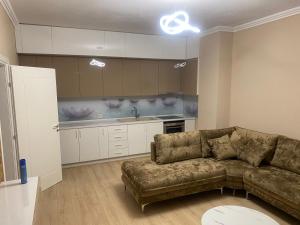 een woonkamer met een bank en een keuken bij Cherry Apartments in Shkodër