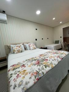 a bedroom with a large bed with a floral blanket at Green It Motel & Hotel in Bragança Paulista