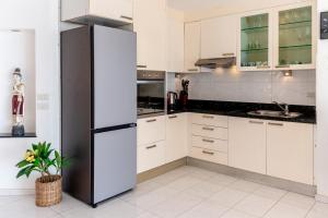 a kitchen with white cabinets and a black refrigerator at Amore Villa by Utalay Koh Chang in Ban Khlong Son
