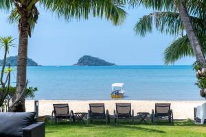 a beach with chairs and a boat in the water at Amore Villa by Utalay Koh Chang in Ban Khlong Son