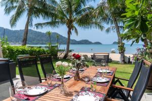 a wooden table with glasses and flowers on a beach at Amore Villa by Utalay Koh Chang in Ban Khlong Son