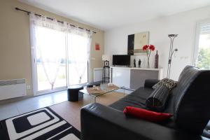 un soggiorno con un divano nero e una TV di L'oree du bois a Livron