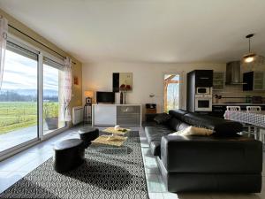 un soggiorno con divano in pelle nera e una cucina di L'oree du bois a Livron